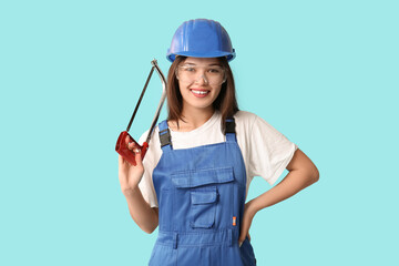 Young female worker with hacksaw on blue background