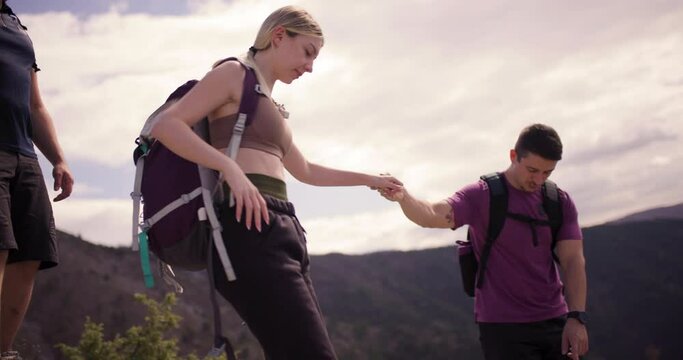 A group of friends on a hiking trip in the mountains, helping each other navigate the rugged terrain. The video captures teamwork, adventure, and the spirit of friendship.