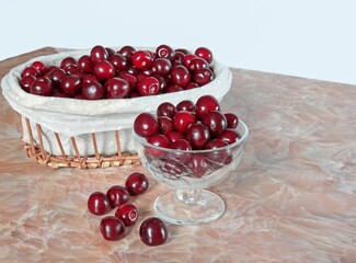 A lot of cherries, red cherries, ripe, natural in a glass vase and in a basket for a healthy diet.