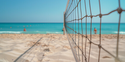A beach volleyball net set up with people playing in the background.