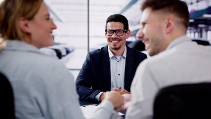 young salesman smiles while handing over the keys to a couple buying a new car