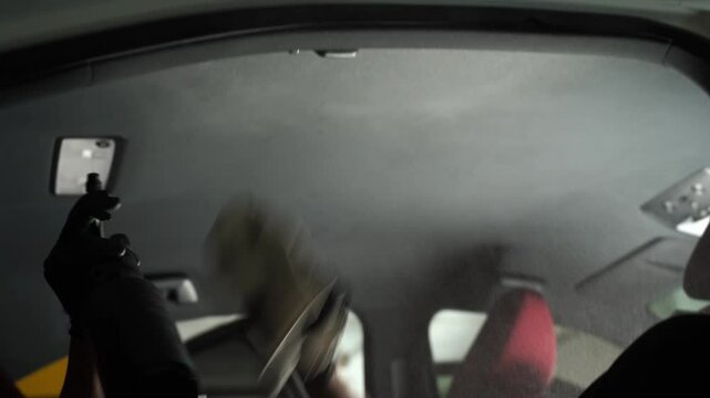 4k video detailing car headliner covering. Spraying detergent on the headliner in car. Hand cleans car ceiling with detergent and microfiber rug.
