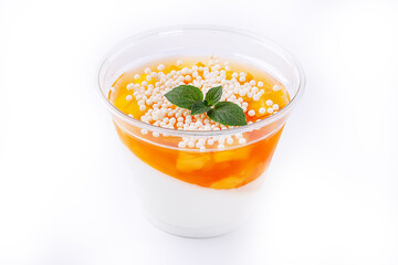 Orange panna cotta with mango slices in a glass on a white ilolate background