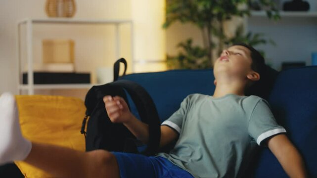 Upset pre-teen boy coming home from school, sitting on couch, peer pressure