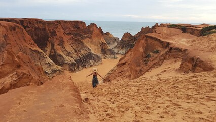mulher caminhando entre as falésias de morro branco, no ceará 