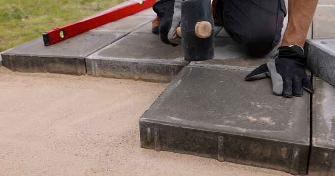 man laying concrete paving slabs with rubber hammer. terrace pavement