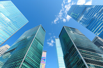 A stunning skyline featuring a row of sleek skyscraper office buildings under a clear blue sky, with a single vibrant advertisement poster on one of the buildings.