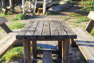Old wooden table and benches in a park on a sunny day