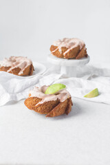 Iced mini bundt cake on a white tray, vanilla bundlette cakes with a clementine lime segment on a white background, small vanilla bundt cakes with an icing glaze
