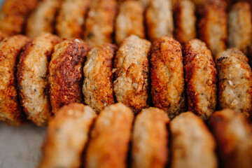 limbazi, Latvia, June 29, 2024 - Close-up of a row of browned, seasoned meat patties, showcasing their texture and crisp exterior. The patties are arranged in a pattern.