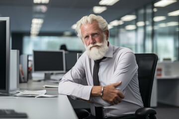 Fototapeta premium Portrait of a mature businessman with a beard seated confidently in an office environment