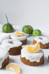 Iced mini bundt cake on a white tray, vanilla bundlette cakeswith a clementine segment on a white background, small vanilla bundt cakes with an icing glaze