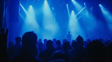 Naklejka premium Crowd of people and enthusiastic fans in front of stage at concert, with bright lights and smoke from a smoke machine creating a vibrant atmosphere. Energy and excitement of a live music performance.