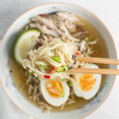 Overhead view of noodles with chili on chopsticks, top view of ramen noodles