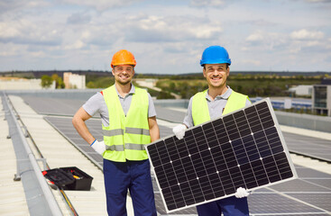 Portrait of a happy men electricians engaged in installation of solar panels on a roof. Work on the...
