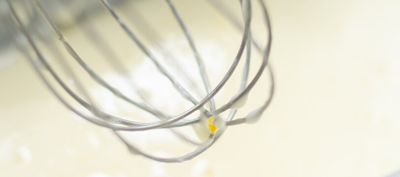 A whisk is sitting in the dough in a loaf tin with a sheet of parchment paper