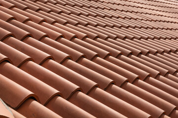Red corrugated roof tile element on a house on a sunny day. Shingles roofing surface tiles overlay pattern and texture.