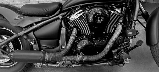 Chrome rear wheel and exhaust on black custom motorbike. v shaped engine. exhaust pipe. tyre wheel. motorcycle. chopper bike. back detail of individual bike. disk brake