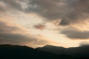 beams Rays of light shining through dark clouds over mountains. dramatic scene. Fairy landscape with dark sky and sunbeam in caucasian mountains. Dilijan.