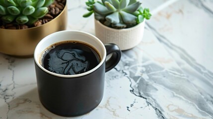 A cup of dark roast coffee in a matte black mug on a marble countertop, with a small pot of succulents nearby