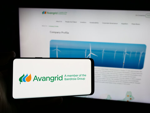 Stuttgart, Germany - 07-03-2024: Person holding mobile phone with logo of American energy services company Avangrid Inc. in front of business web page. Focus on phone display.
