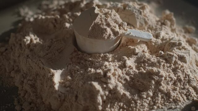 Protein powder with measuring spoon on table, close-up