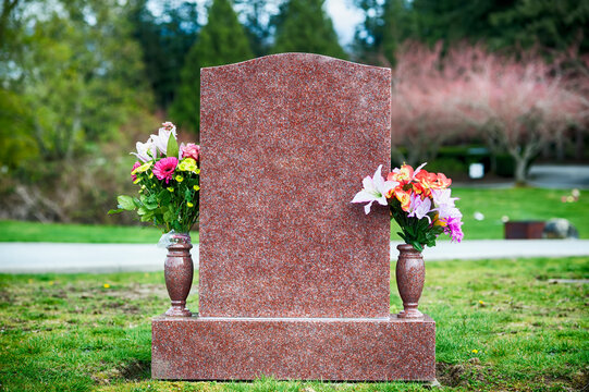 Flowers on a blank tombstone in natural surroundings.