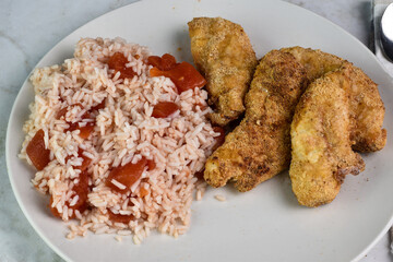 chicken  fingers served   with  rice and tomatos