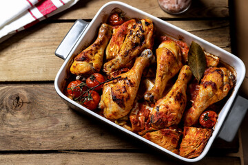 Oven roasted chicken drumsticks casserole with cabbage and tomatoes on wooden table high angle view