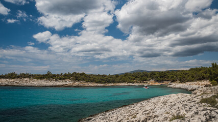 A small boat on the turquoise blue water along the rocky shore of Atspas beach on the island of Thassos in Greece