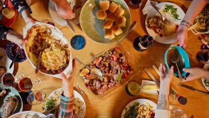 4K Ultra HD image of Top Down Shot of People Gathered Around Dining Table for Friendsgiving Party Passing Plates of Food