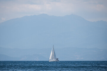 Fototapeta premium A white sailing boat on the horizon sails on a calm sea