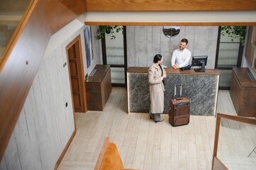 Female guests come with bags and suitcases to the hotel reception in the lobby