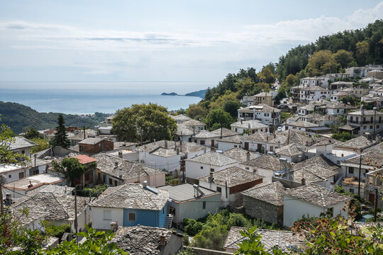 A view of the stone roofs and close-knit houses of the village of Panagia on the island of Thassos. The sea can be seen in the distance.