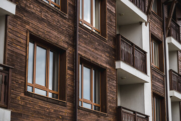 A beautiful wooden facade with balconies and windows that shine in the light of the setting sun