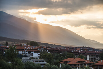 View of Bansko and the surrounding mountains as the setting sun breaks through the clouds, Bulgaria