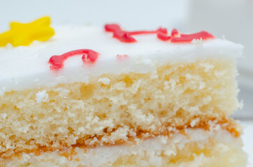 A slice of white cake with color frosting on top