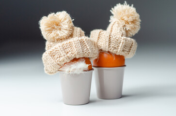 The orange eggs with hats on top of them in cups