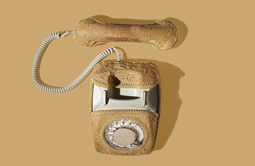 Old yellow phone with dial plate  on orange pastel background