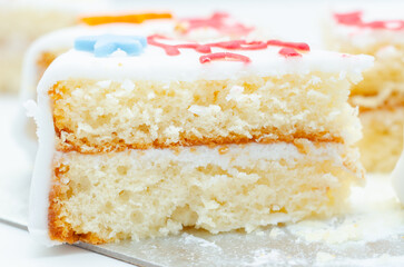 A slice of white cake with color frosting on top