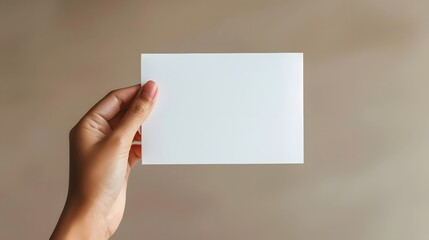 Hand holding greeting card mockup on clean background. White empty paper for text. Invitation, letter, gift, certificate template

