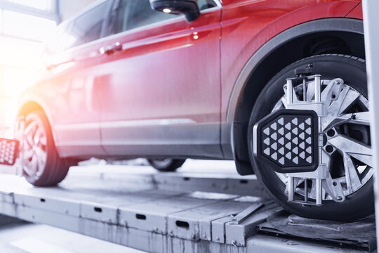 Closeup car wheel alignment on stand with sensors check in service station. Vehicle inside garage workshop for auto camber fixing work.