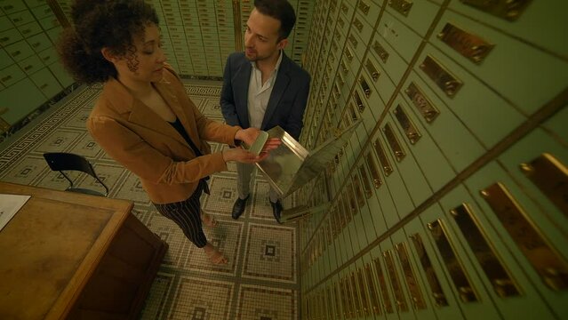 A couple accessing a secure deposit box in a bank vault to examine their valuable assets