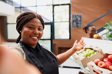 Black woman promotes eco-friendly products, inspiring online audiences to buy sustainable groceries for a healthy and trendy life. Female vendor taking video of bio food store for social media.