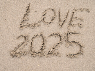 Sign love and 2025 on beach sand. Hand made message