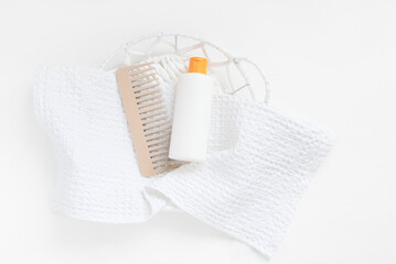 Plastic white bottle hair comb on towel. Mockup template for hair care products.