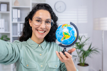Smiling woman holding a globe in an office setting, representing global business and education