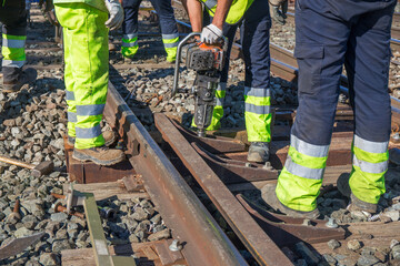 Personnel carrying out repairs to change sleepers in railway infrastructure with different hand tools.