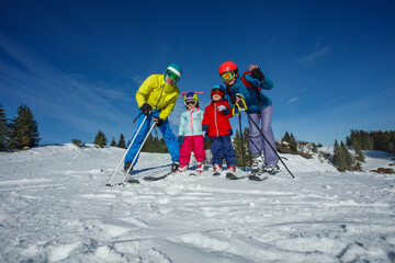 A happy family posing together for photo on snowy ski slopes