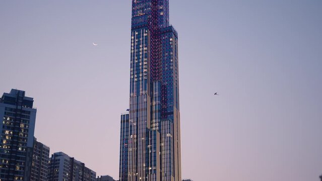 two kites fly next to landmark 81 skyscraper with colorful lights in ho chi minh city HCMC saigon vietnam at sunset under the moon